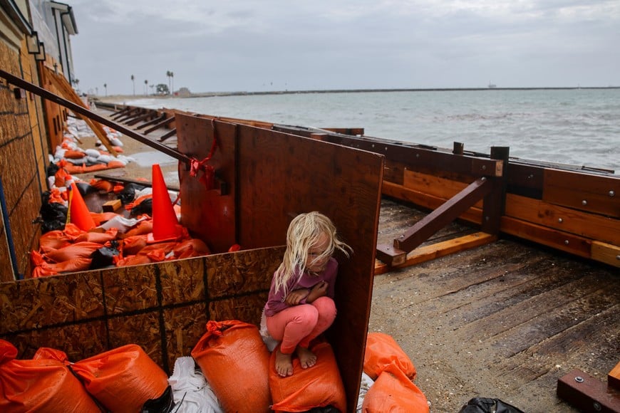 A girl takes shelter from sea spray as Post-Tropical Cyclone Rachel impacts the coastline in Long Beach, California, U.S., October 11, 2026. REUTERS/Daniel Cole