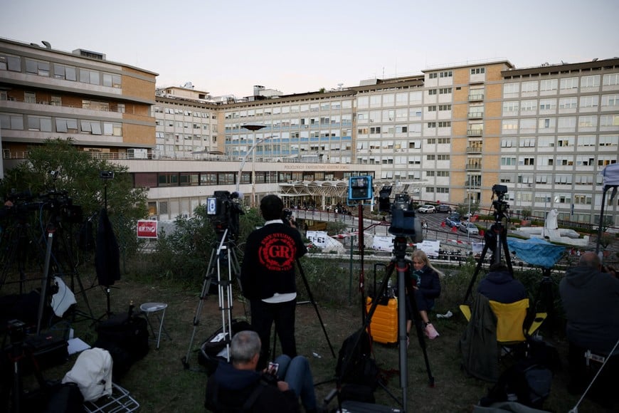 Members of the media work outside Gemelli Hospital, where Pope Leo is hospitalised to undergo surgery to remove a lung nodule, in Rome, Italy, October 13, 2026. REUTERS/Stoyan Nenov REFILE - CORRECTING FROM "AHEAD OF SURGERY" TO "TO UNDERGO SURGERY".