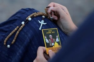 Una mujer sostiene un rosario y una estampa con la imagen del Papa León XIV a las afueras del Hospital Gemelli, donde el Pontífice recibe tratamiento para el cáncer de pulmón tras una cirugía para extirparle parte del pulmón derecho. Crédito: REUTERS/Yara Nardi