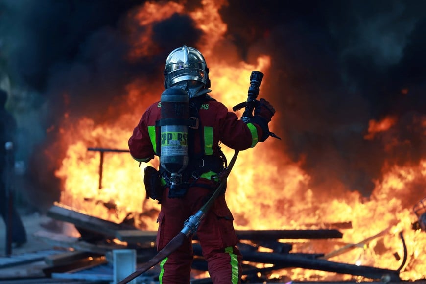 A French firefighter works to extinguish a burning barricade amid clashes during a day of demonstrations against the cost of living and rising fuel prices in Paris as part of nationwide protests called by the "Yellow Vests" movement, joined by French high school and university students, teachers and parents demanding better school conditions and government action, as well as labour unions, workers, farmers and retirees, France, October 17, 2026. REUTERS/Stephanie Lecocq