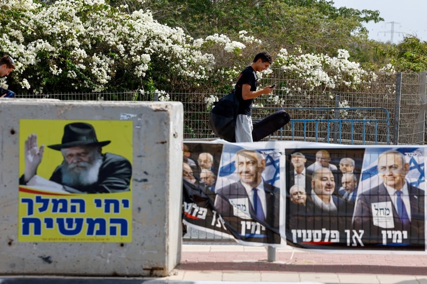 A person walks near an election banner with an image of Israel's Prime Minister Benjamin Netanyahu, leader of Likud party, and a poster with an image of the late Rabbi Menachem Mendel Schneerson, known as the the Lubavitcher Rebbe, in Sderot, near Israel's border with Gaza, in southern Israel, October 18, 2026. REUTERS/Amir Cohen