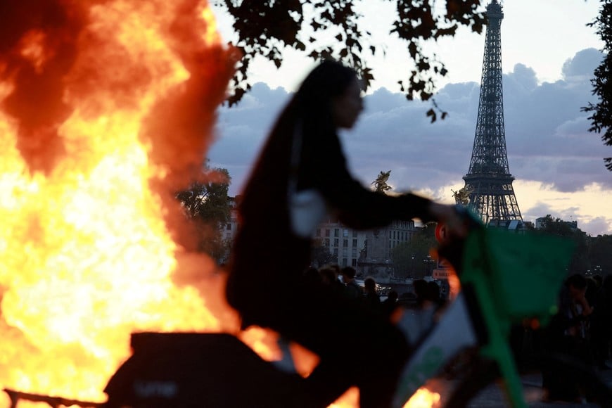 FILE PHOTO: A woman rides a bicycle past a burning barricade near the Tuileries Garden with the Eiffel tower in the background, amid clashes during a day of demonstrations against the cost of living and rising fuel prices in Paris as part of nationwide protests called by the "Yellow Vests" movement, joined by French high school and university students, teachers and parents demanding better school conditions and government action, as well as labour unions, workers, farmers and retirees, France, October 17, 2026.  REUTERS/Stephanie Lecocq/File Photo