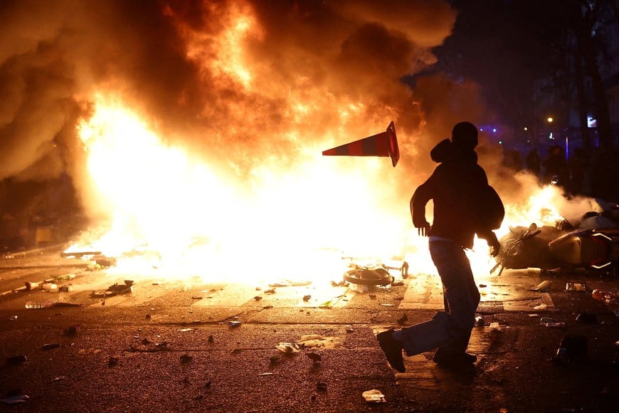 A man throws a plastic traffic cone through a burning barricade amid clashes during a day of demonstrations against the cost of living and rising fuel prices in Paris as part of nationwide protests called by the "Yellow Vests" movement, joined by French high school and university students, teachers and parents demanding better school conditions and government action, as well as labour unions, workers, farmers and retirees, France, October 17, 2026. REUTERS/Abdul Saboor TPX IMAGES OF THE DAY REFILE - CORRECTING ACTION FROM "A PROTESTERS SIT ON CHAIRS FROM A VANDALIZED SHOP AS THEY BLOCK A STREET" TO "A MAN THROWS A PLASTIC TRAFFIC CONE THROUGH A BURNING BARRICADE".