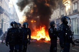 Un incendio arde mientras agentes de policía con equipo antidisturbios montan guardia durante los disturbios civiles, un día después de una jornada nacional de manifestaciones contra el costo de vida y el aumento de los precios del combustible, en París, Francia, el 18 de octubre de 2026. Crédito: REUTERS/Abdul Saboor