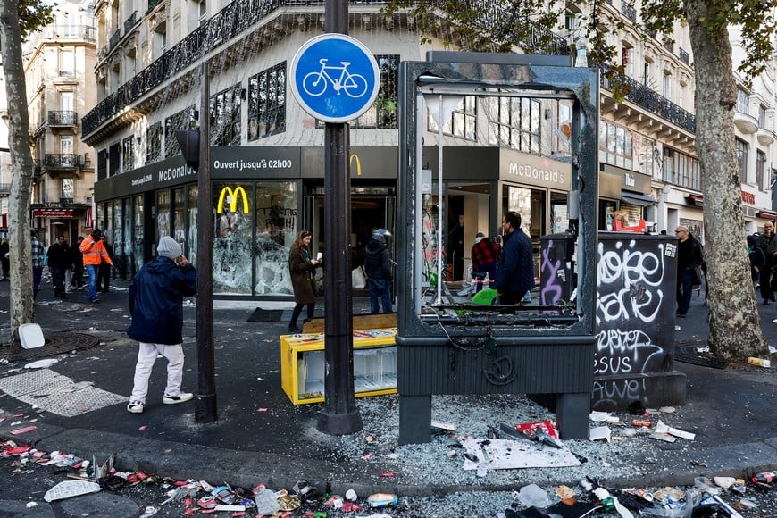 People walk past the damaged window of a McDonald's, the day after clashes during a national day of demonstrations against the cost of living and rising fuel prices, in Paris, France, October 18, 2026. REUTERS/Benoit Tessier