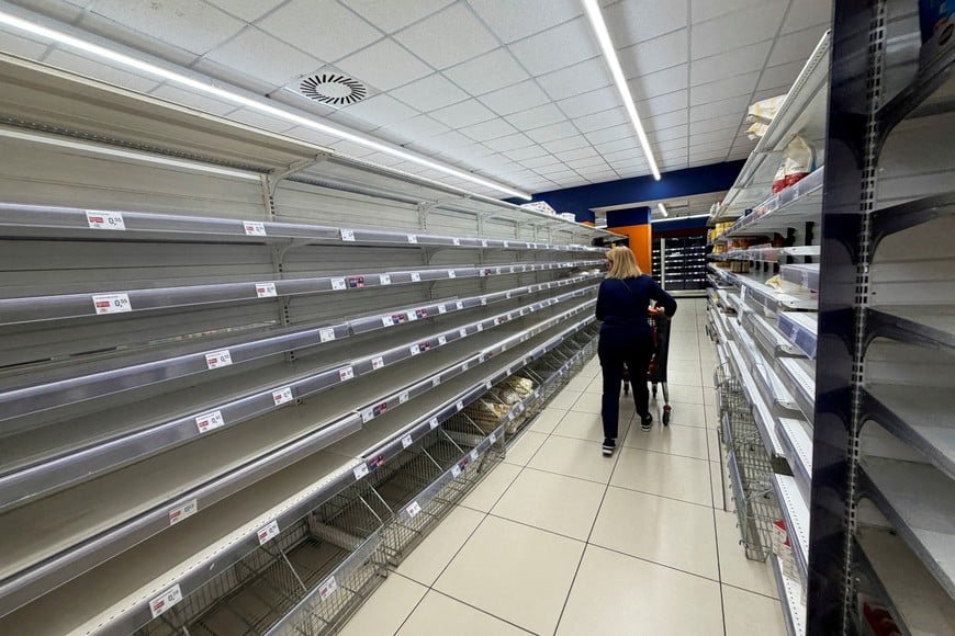FILE PHOTO: A shopper walks next to empty shelves at a supermarket in Naples, amid truckers' protest over soaring fuel and transport costs, which disrupted supplies across Sicily and southern Italy, October 20, 2026. Picture taken with a mobile phone. REUTERS/Ciro De Luca TPX IMAGES OF THE DAY/File Photo