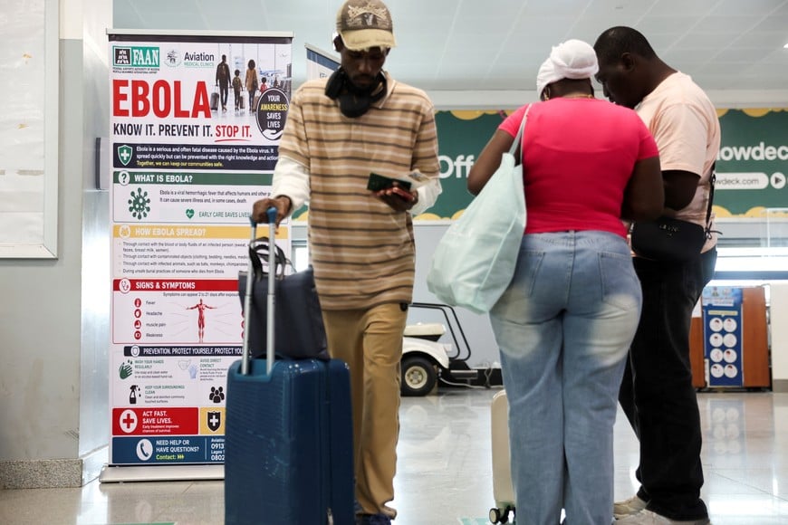 Travellers next to a banner displayed by a health screening station at Murtala Muhammed International Airport following reports of an Ebola case in Nigeria, in Lagos, Nigeria, October 22, 2026. REUTERS/Sodiq Adelakun