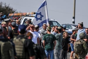 Colonos israelíes se congregan mientras las fuerzas israelíes custodian el lugar tras un tiroteo en Hebrón, en la Cisjordania ocupada por Israel. Crédito: REUTERS/Ammar Awad