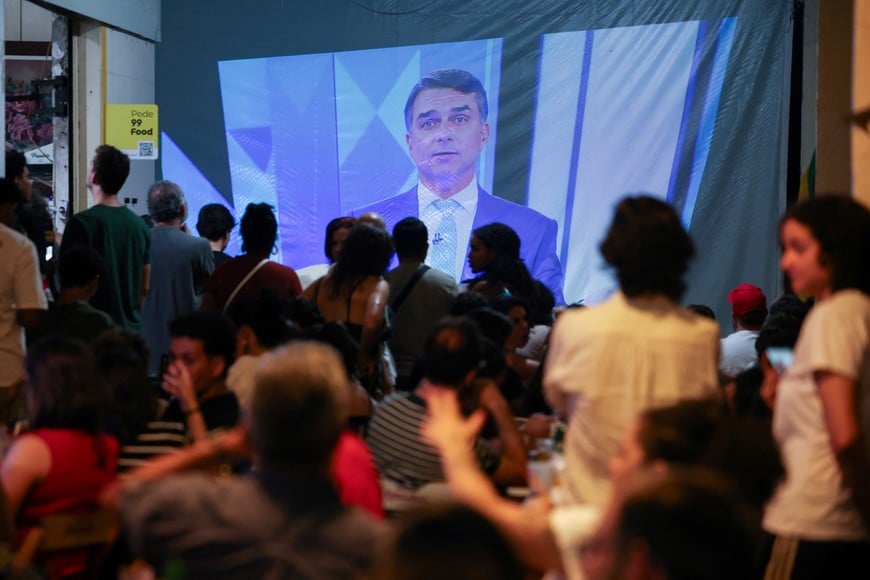 People watch a televised debate between Brazilian presidential candidate Flavio Bolsonaro of the right-wing Liberal Party (PL) and Brazilian President Luiz Inacio Lula da Silva of the leftist Workers' Party (PT), who is seeking reelection, ahead of the presidential election runoff, in Brasilia, Brazil October 23, 2026. REUTERS/Adriano Machado