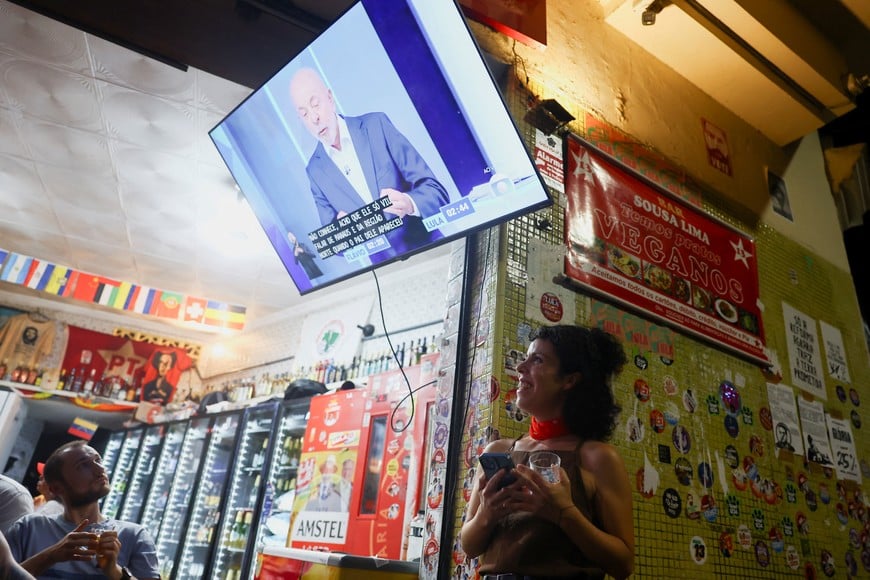 People watch a televised debate between Brazilian presidential candidate Flavio Bolsonaro of the right-wing Liberal Party (PL) and Brazilian President Luiz Inacio Lula da Silva of the leftist Workers' Party (PT), who is seeking reelection, ahead of the election runoff, in Rio de Janeiro, Brazil October 23, 2026. REUTERS/Pilar Olivares