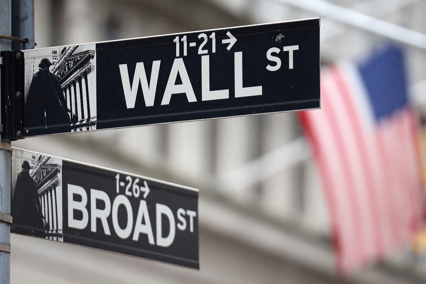 A Wall Street sign hangs in front of a U.S. Flag outside the New York Stock Exchange (NYSE) before the Federal Reserve announcement in New York City, U.S., September 18, 2024. REUTERS/Andrew Kelly