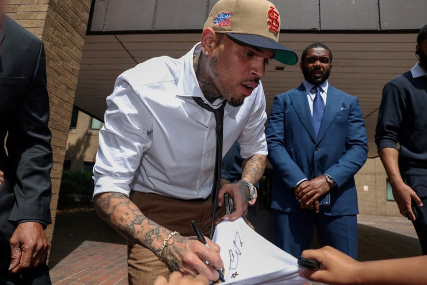 U.S. singer Chris Brown, who has been charged with inflicting grievous bodily harm in what prosecutors said was an "unprovoked attack" in a London nightclub in 2023, gives an autograph as he leaves Southwark Crown Court in London, Britain, July 24, 2026. REUTERS/Toby Melville TPX IMAGES OF THE DAY