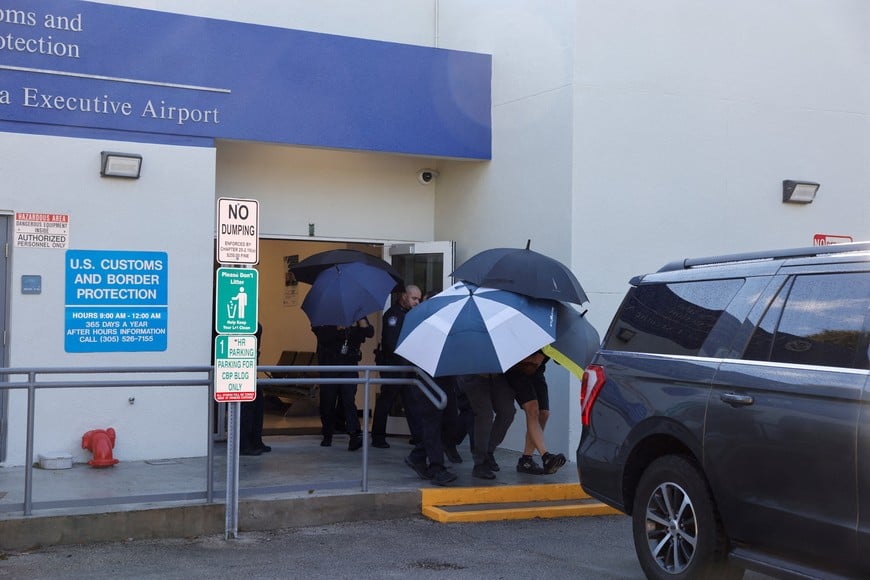 A group of people, shielded by umbrellas, leaves the US Customs and Border Protection facility at Opa-locka Executive Airport following Brazilian Senator Flavio Bolsonaro's arrival in the United States, near Miami, Florida, US, October 28, 2026. REUTERS/Eva Marie Uzcategui REFILE - CORRECTING INFORMATION FROM "BRAZILIAN SENATOR FLAVIO BOLSONARO IS ESCORTED" TO "A GROUP OF PEOPLE, SHIELDED BY UMBRELLAS, LEAVES"