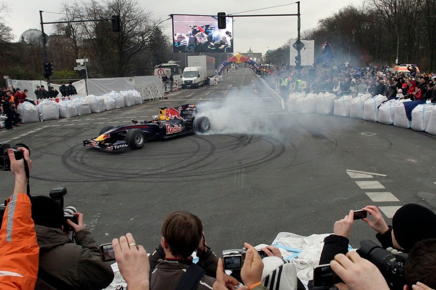 New Formula One world champion Sebastian Vettel drives down the Strasse des 17 Juni boulevard in Berlin, November 27, 2010. Vettel will drive his Red Bull on a lap of honour through central Berlin on Saturday in front of tens of thousands of German fans, his team said. He is due to compete in the exhibition Race of Champions in Duesseldorf later that day, will make a stop in the capital to drive his F1 car down the Strasse des 17 Juni boulevard that ends at the Brandenburg Gate in the heart of the city. REUTERS/Tobias Schwarz (GERMANY - Tags: SPORT MOTOR RACING) berlin alemania Sebastian Vettel piloto campeon de la formula1 automovilismo piloto festeja festejo con su auto escuderia red bull