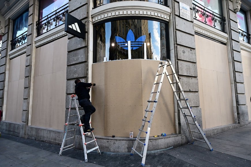 A man works on covering the facade of a store in preparation for the possibility of looting and street riots allegedly being coordinated through the social media movement and tag Blocus, whose alleged initial instigator and other coordinators were arrested on Friday. in Madrid, Spain, October 30, 2026. REUTERS/Juan Barbosa