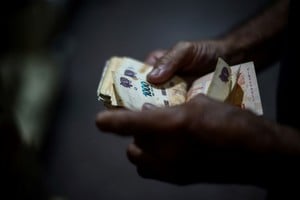 Luis Relinque, 75, count bills as he buys alfajores and other sweets to resell from his home to make ends meet, as his pension is not enough, in Buenos Aires, Argentina, February 14, 2025. Relinque receives the minimum monthly pension, which in October wasis small dog. Treats cards and enjoy a meal, but that has also stopped. REUTERS/Tomas Cuesta   PESOS BILLETES