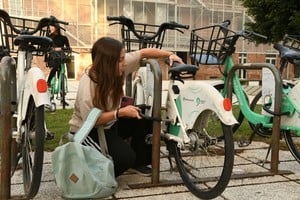 Una joven destraba una bici pública. “Algunas están muy pesadas”, dice. Foto: Manuel Fabatía
