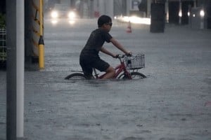 Un niño cruza en bicicleta una calle inundada este lunes en Ichikawa, Japón.